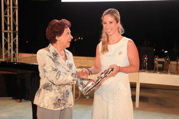 A member of the Stavros Niarchos Foundation accepts an award, and shakes the hand of the woman who gives it